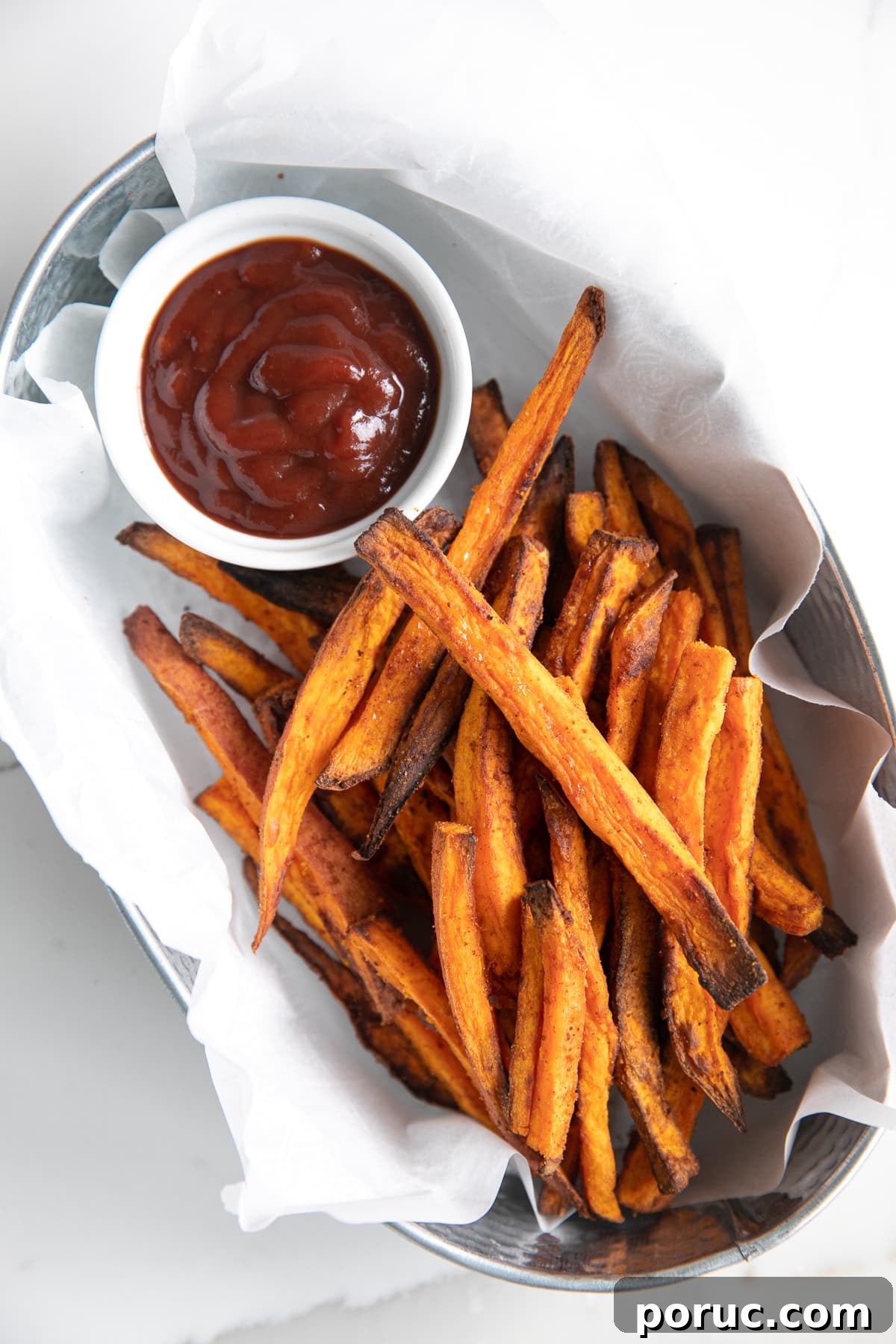 Crispy sweet potato fries made in the air fryer and served in a small metal tin with ketchup.