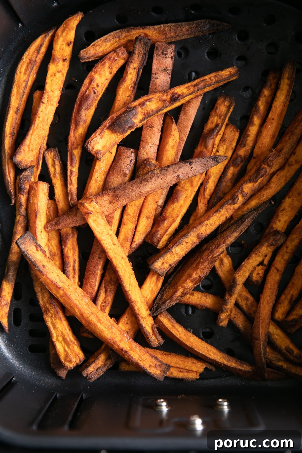 Overhead image looking into the basket of an air fryer filled with cooked sweet potato fries.