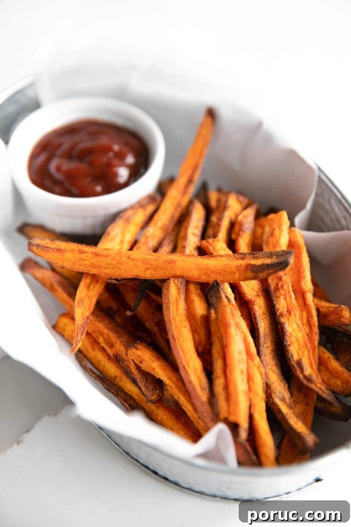 Crispy sweet potato fries made in the air fryer and served in a small metal tin with ketchup.