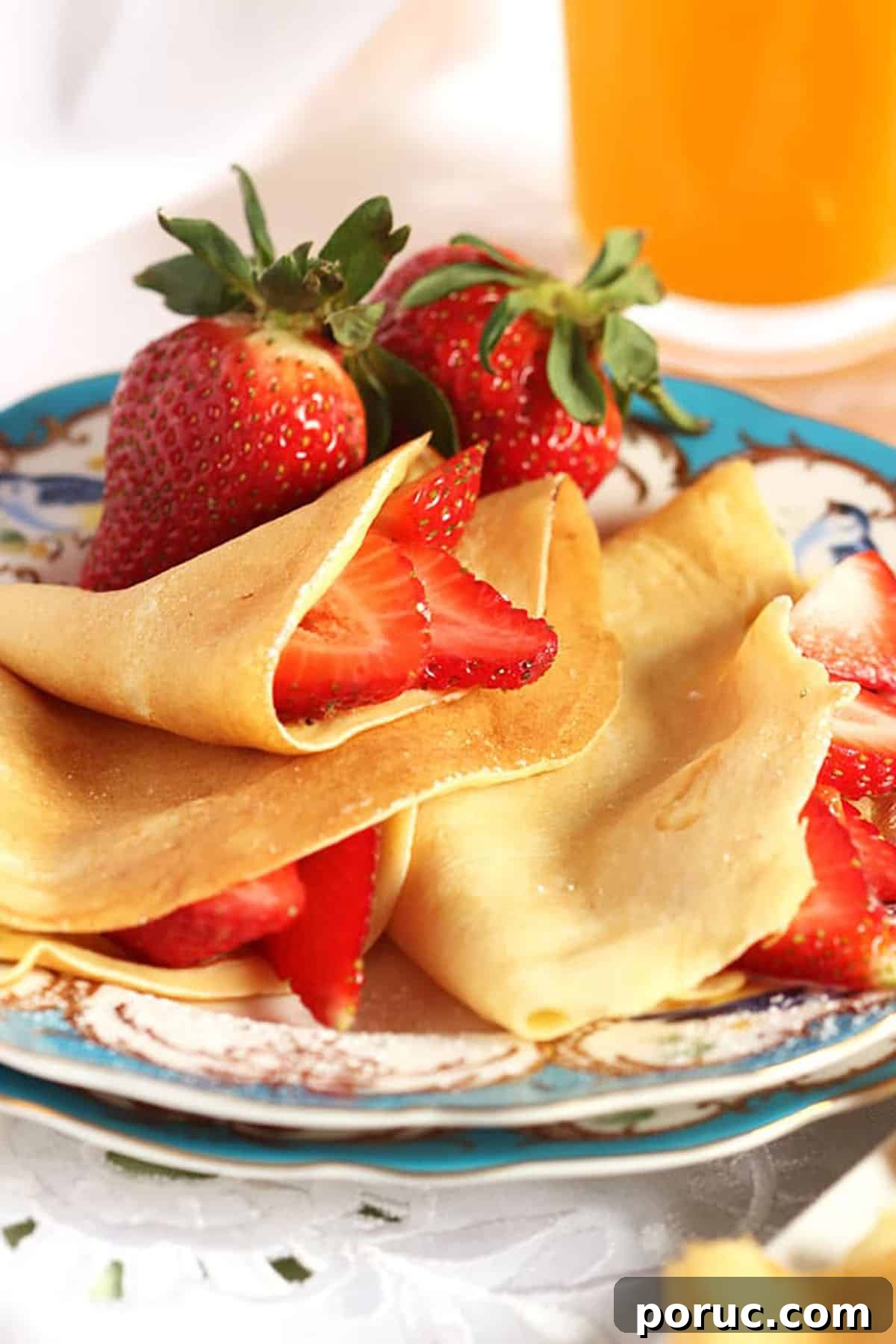 Homemade Crepes: Sweet and Savory Recipes for Any Meal 3 French Crepes stuffed with sliced strawberries on a blue and white plate.