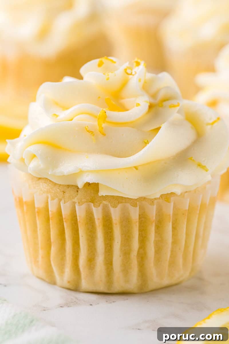 Zesty Lemon Cupcakes Recipe with Simple Glaze 2 closeup of a lemon cupcake topped with frosting and lemon zest.