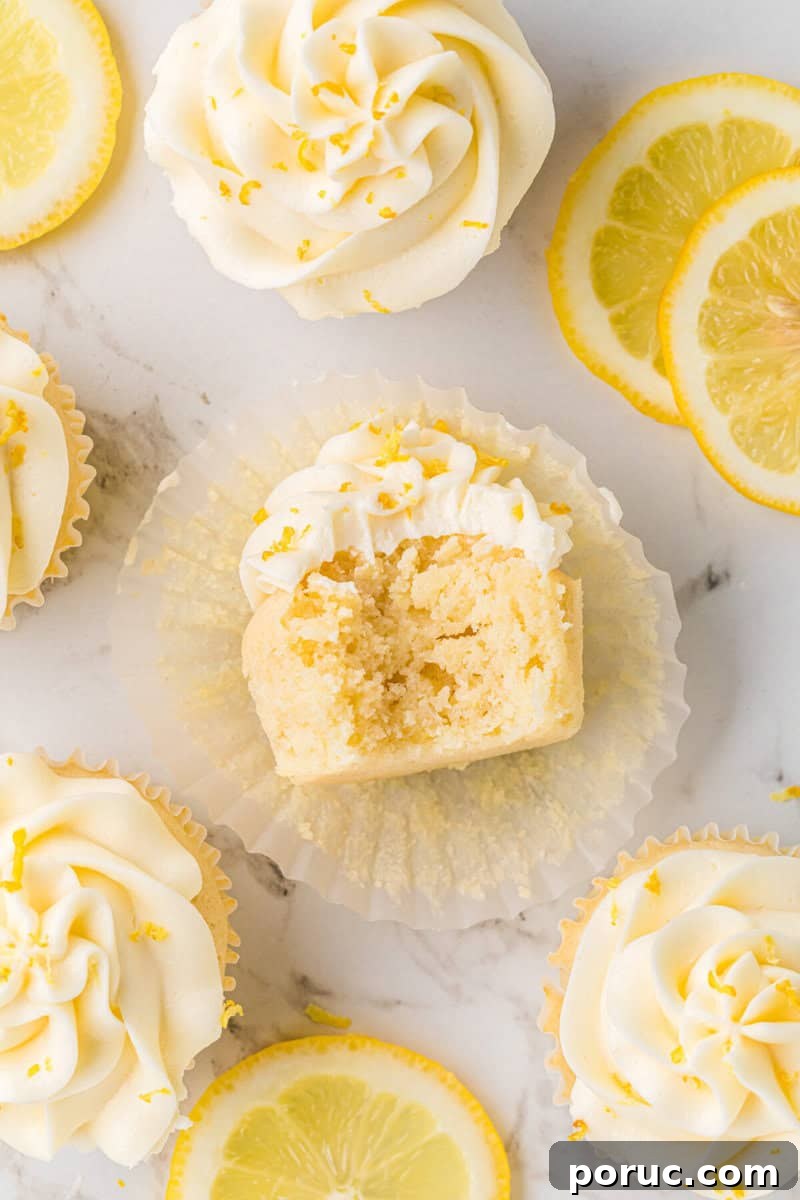 Zesty Lemon Cupcakes Recipe with Simple Glaze 12 lemon cupcake with a bite taken out of it to show the inside.
