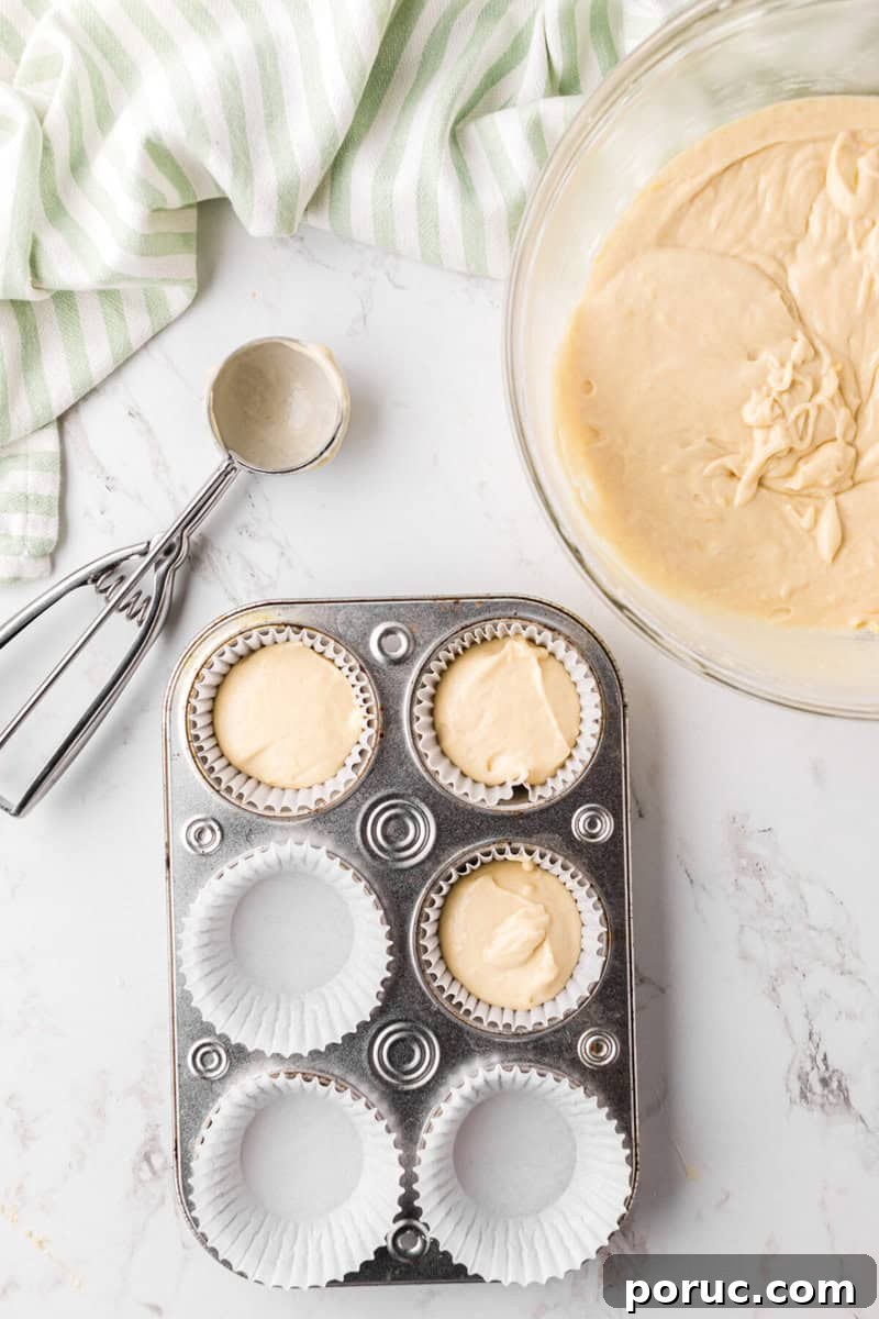 Zesty Lemon Cupcakes Recipe with Simple Glaze 7 scooping the cupcake batter into the cupcake liners in the pan.