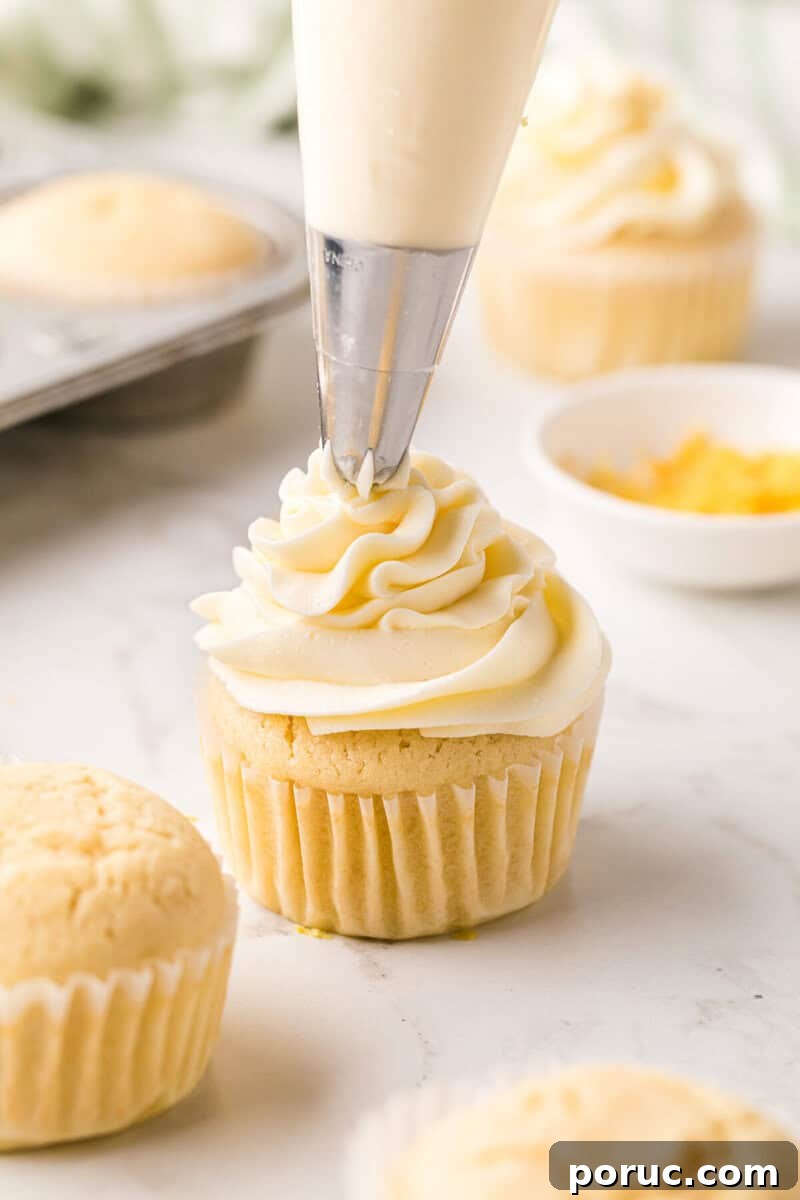 Zesty Lemon Cupcakes Recipe with Simple Glaze 9 topping a lemon cupcake with the frosting.