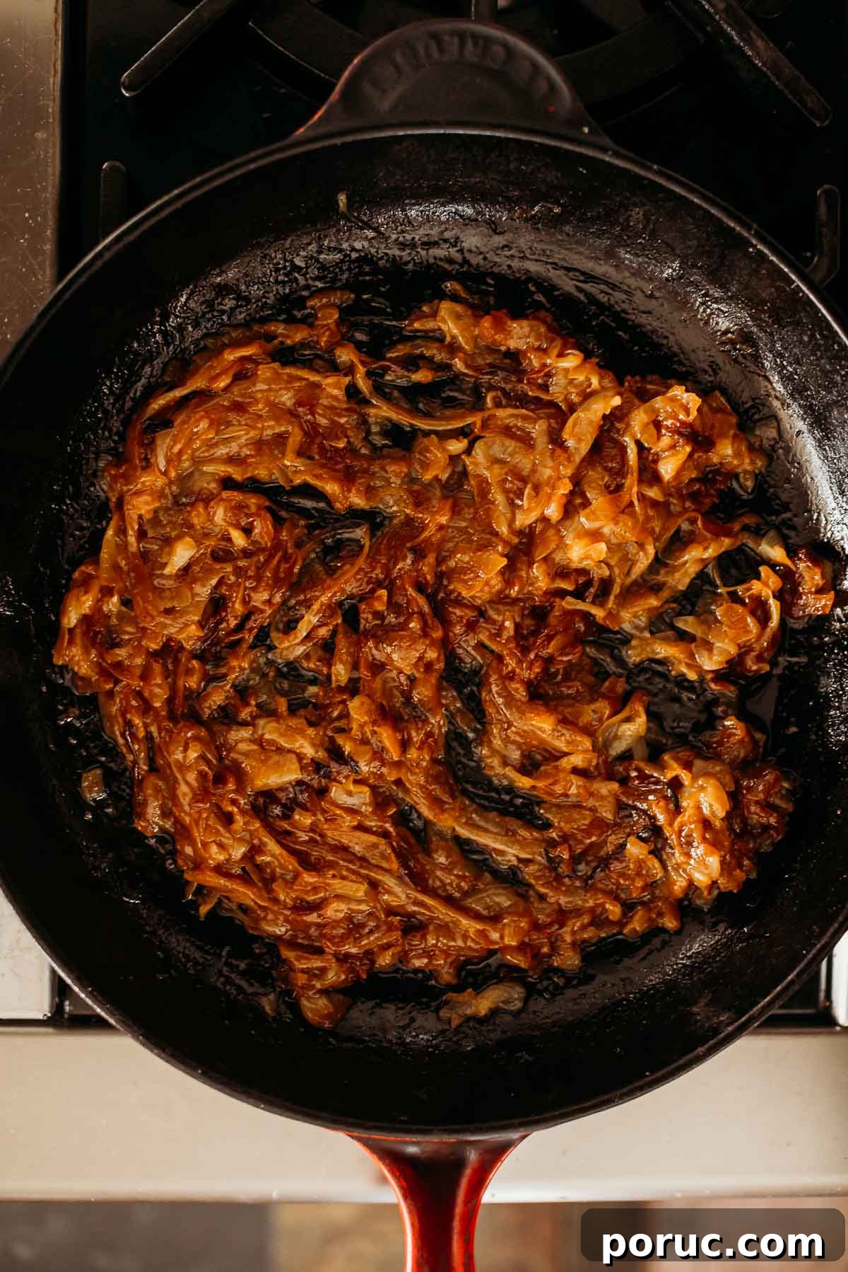 Caramelized onions in a cast iron skillet on a stovetop.
