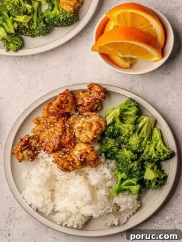 A plate of breaded orange chicken with white rice and steamed broccoli.
