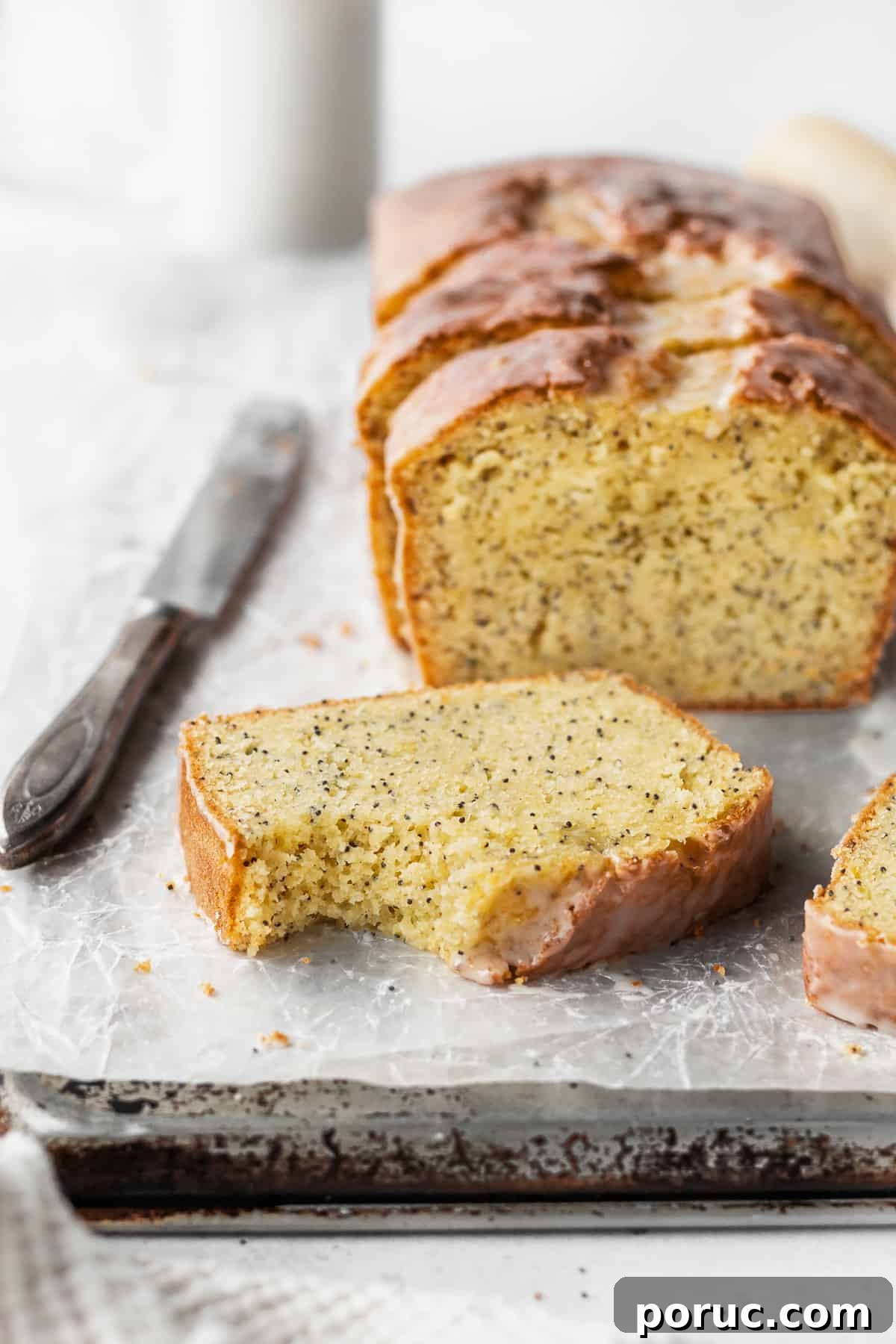 Gluten-Free Lemon Poppy Seed Cake Recipe 6 A bitten slice of gluten free lemon bread with the loaf in the background.