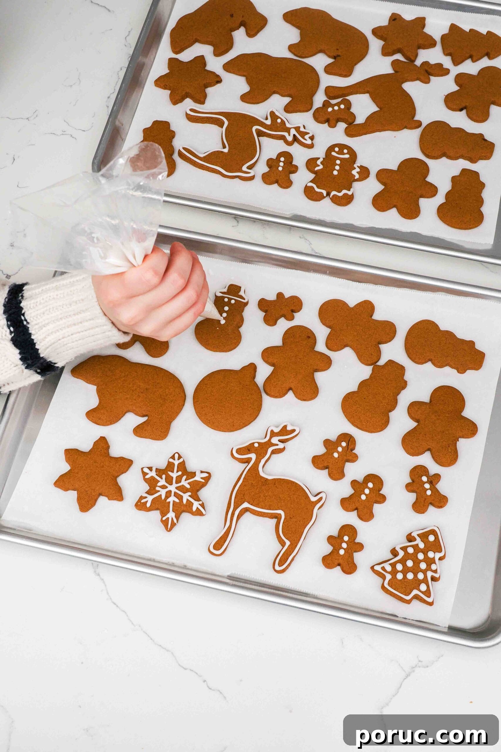 Classic Gingerbread Cookies Recipe for Crisp, Spiced Treats 14 A hand pipes icing onto gingerbread cookies.