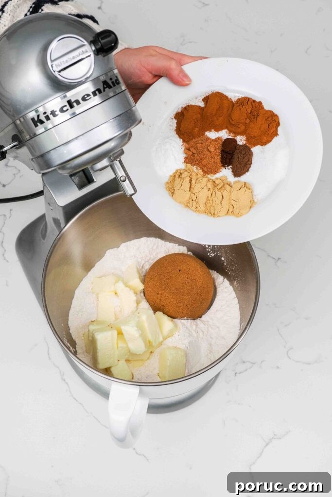 Classic Gingerbread Cookies Recipe for Crisp, Spiced Treats 4 Spices being added to a mixer bowl with flour, brown sugar, and butter.
