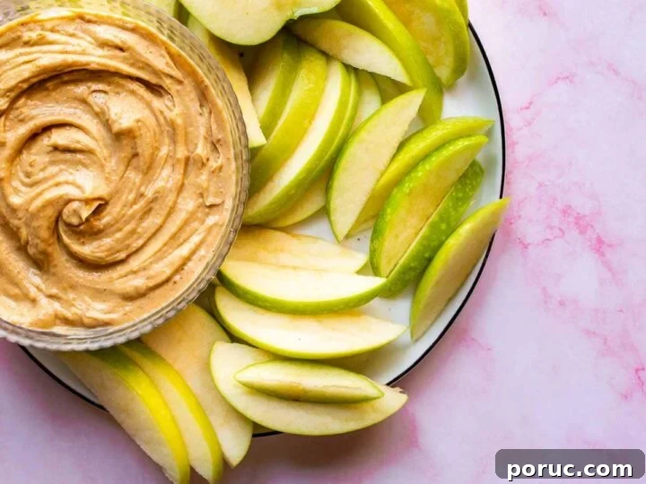 Pink background with a plate of green sliced apples and brown dip on it.