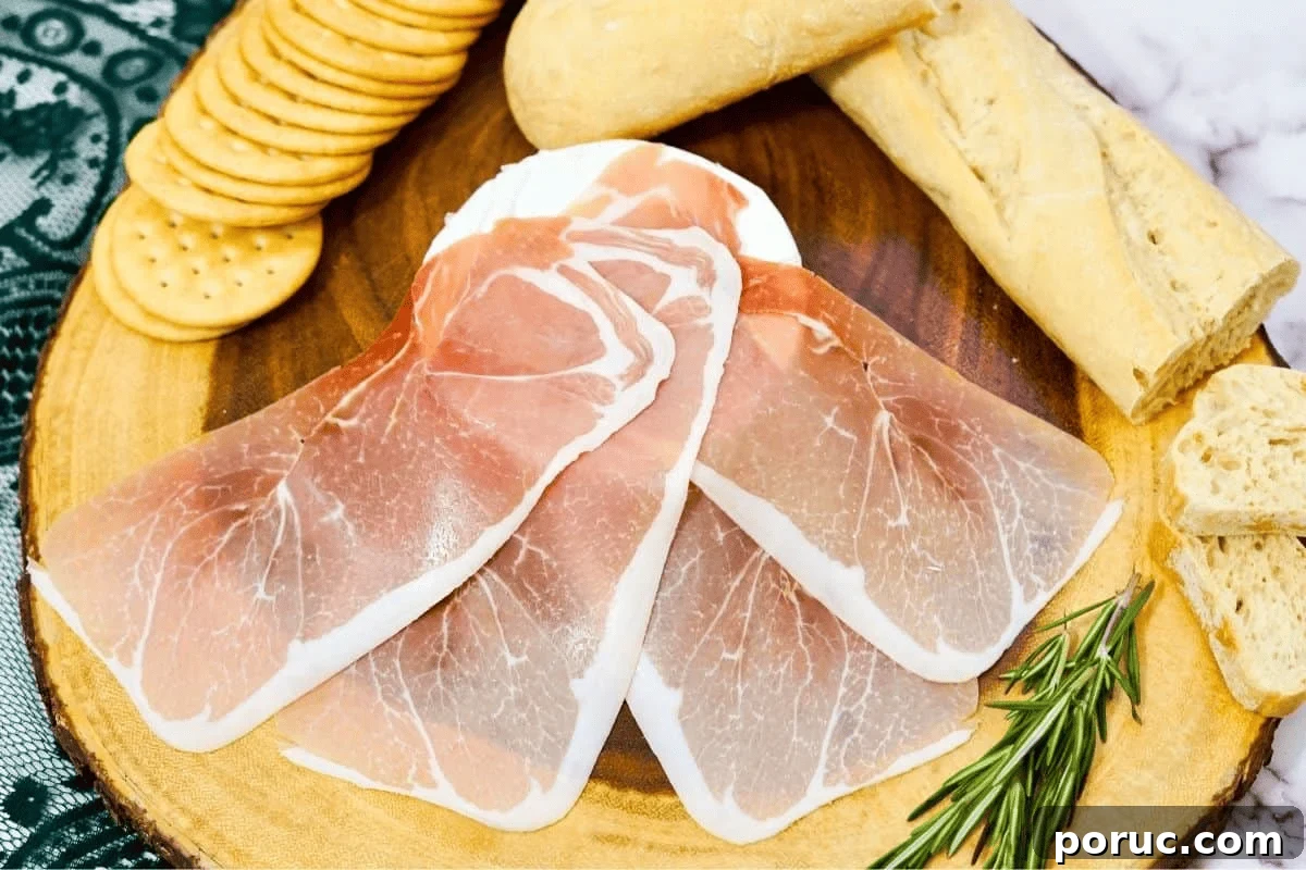 Prosciutto-Wrapped Brie: Baked Appetizer with Honey & Herbs 4 prosciutto slices on brie cheese.