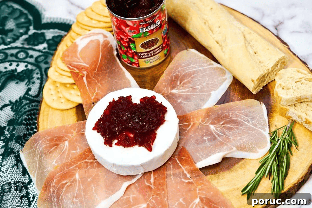 Prosciutto-Wrapped Brie: Baked Appetizer with Honey & Herbs 5 Brie cheese with prosciutto with cranberry sauce.