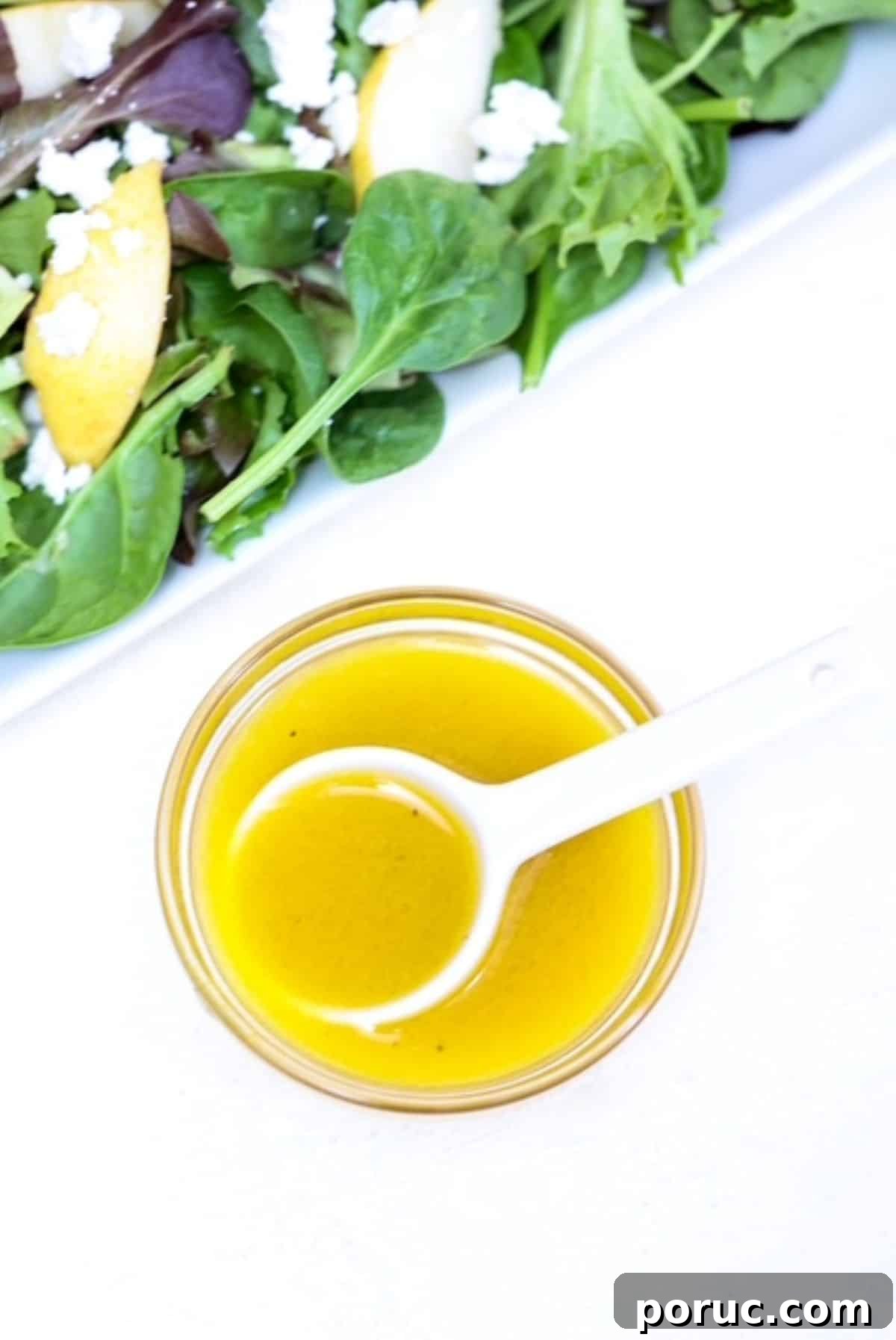 Tangy Apple Cider Vinaigrette Recipe for Salads and Marinades 2 Apple cider vinaigrette dressing in a small bowl with a white spoon and a salad to the side.