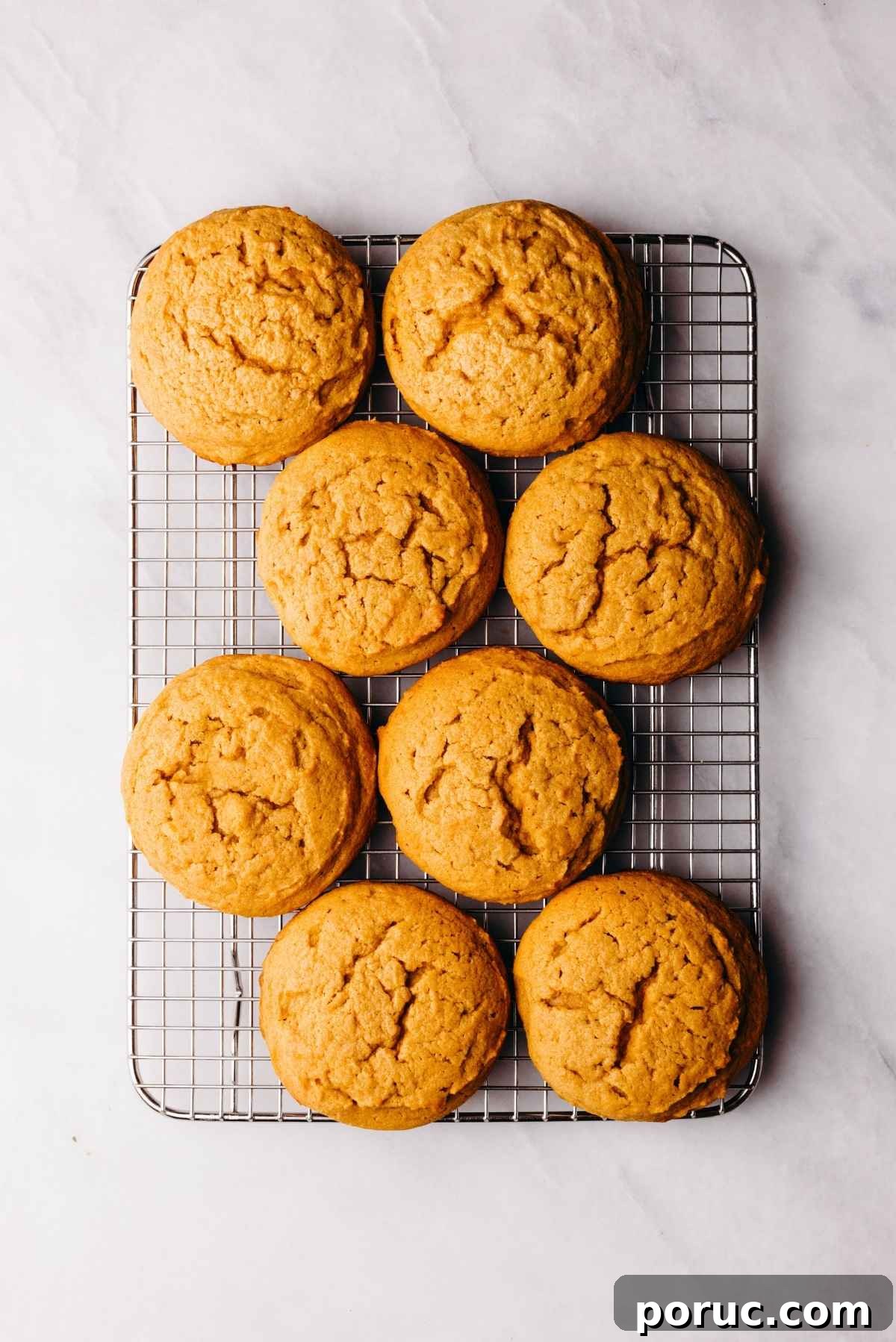 Eight pumpkin whoopie pie cakes cooling on a wire cooling rack.