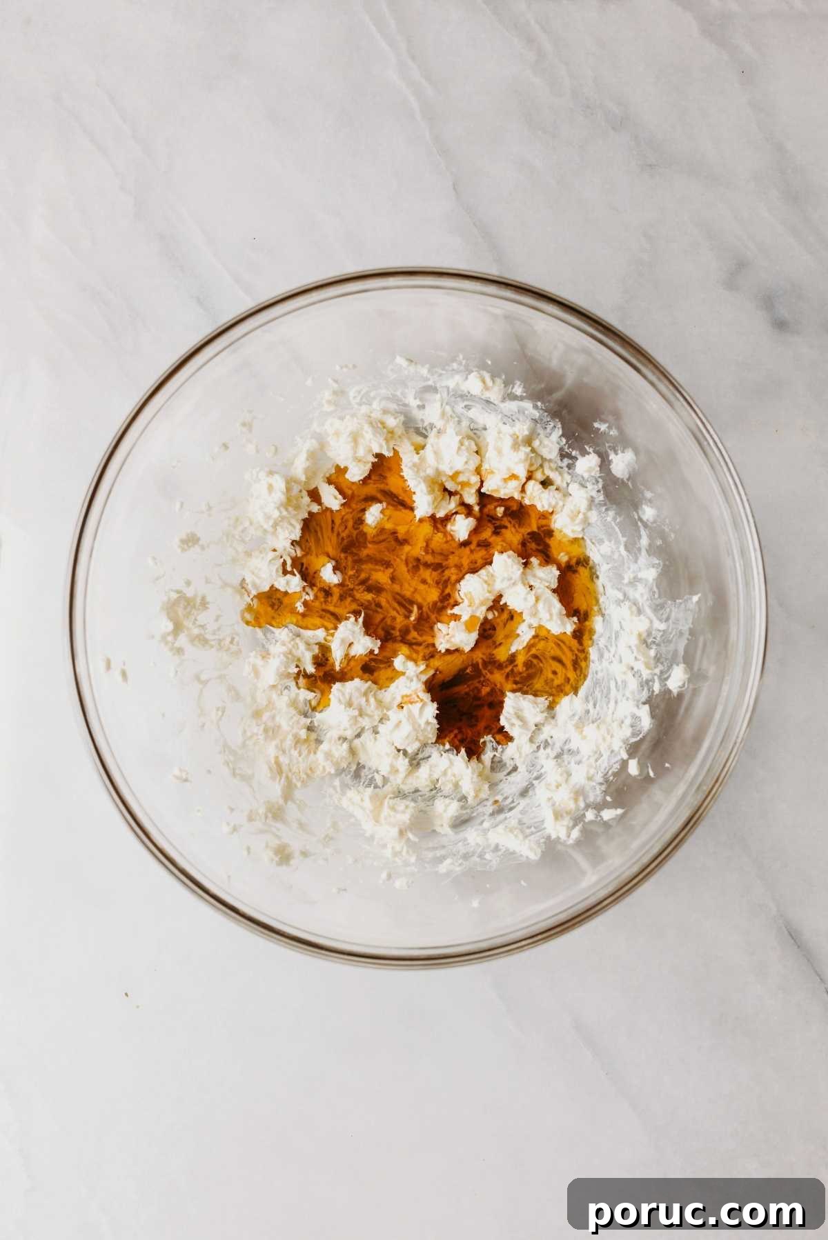 Vanilla extract and maple syrup added to the cream cheese butter mixture in a large glass bowl.