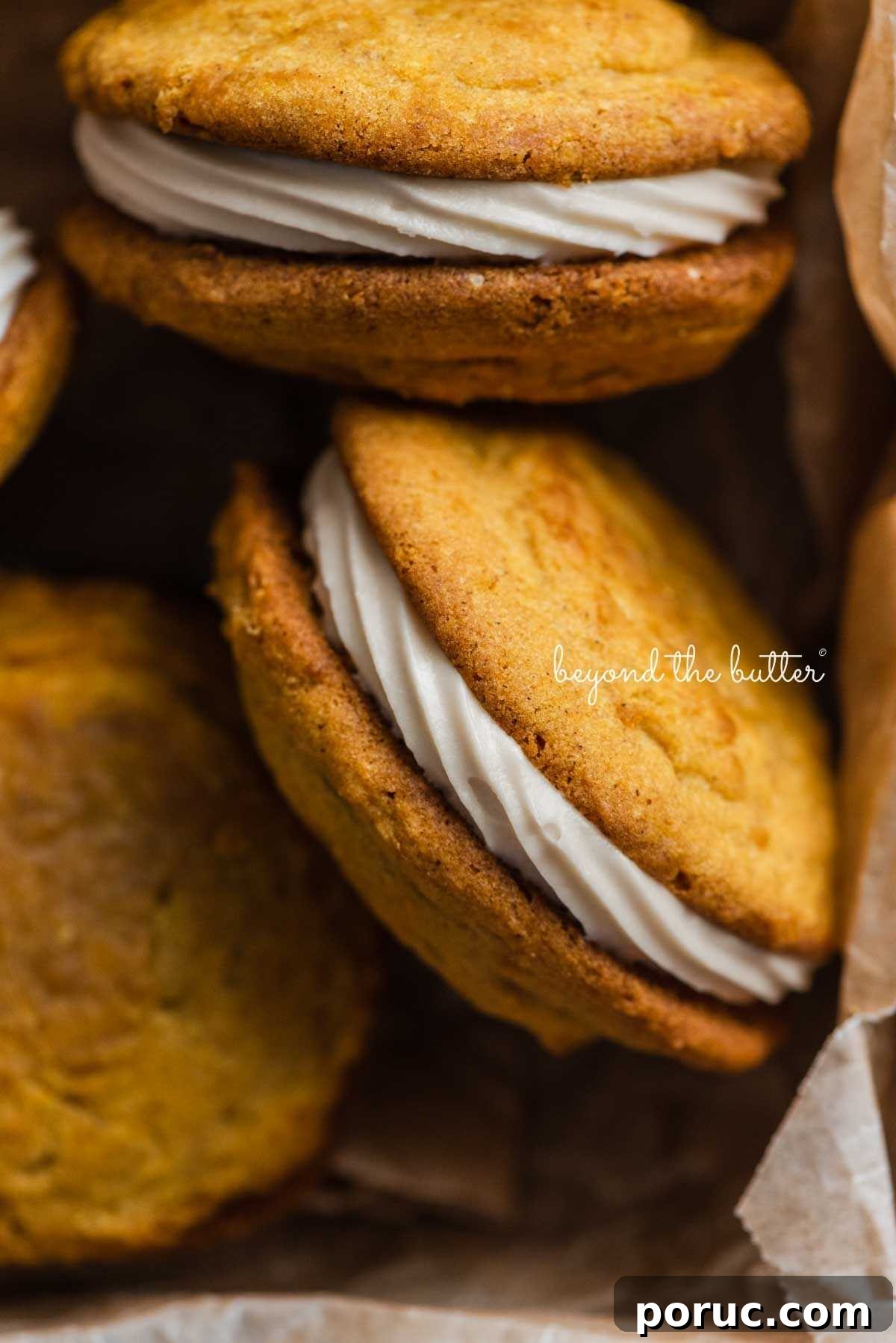Pumpkin whoopie pies randomly positioned in a parchment paper lined baking tin.