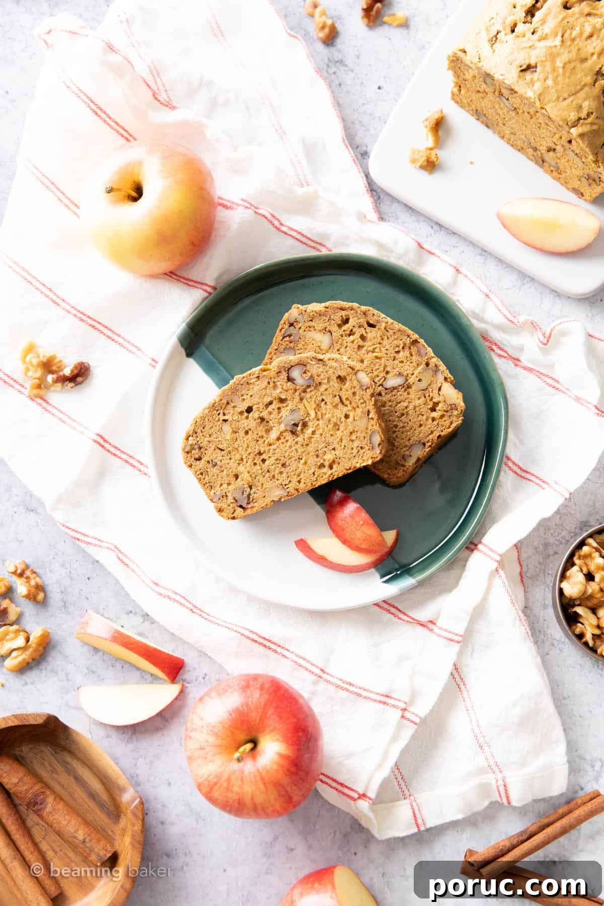 Moist Homemade Apple Bread Recipe for Fall Baking 4 two slices of apple cinnamon bread with walnuts on a green and white plate atop a cloth with apples