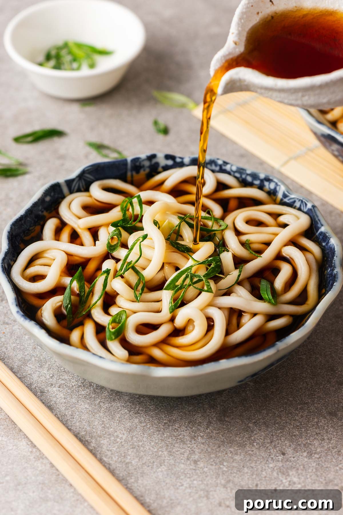 Kake Udon: Classic Japanese Broth Noodle Soup Recipe 12 Pouring kake udon noodle broth over a Japanese bowl with udon noodles.
