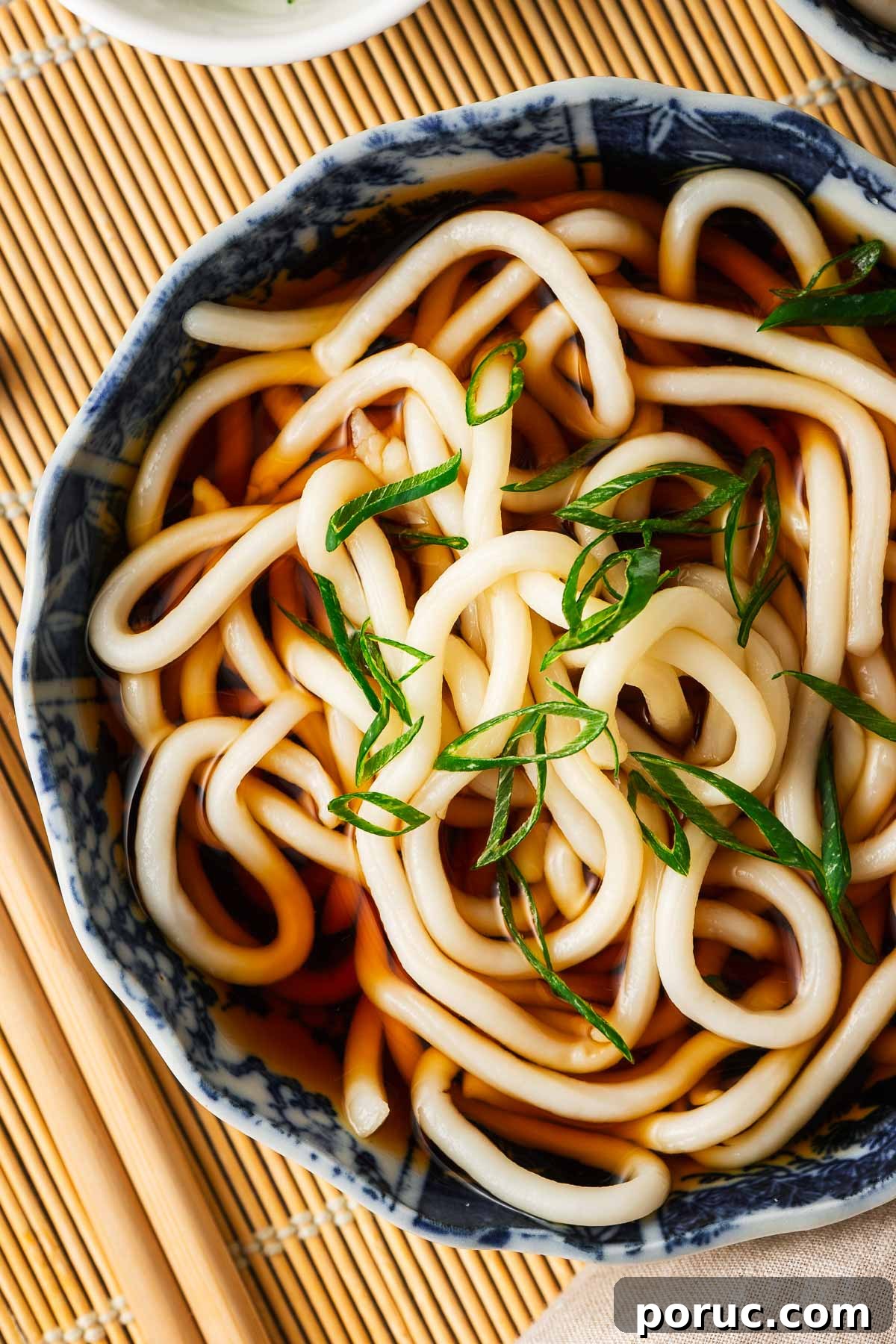 Kake Udon: Classic Japanese Broth Noodle Soup Recipe 3 Thick and chewy udon noodles in a bowl of udon broth scattered with sliced green onions.