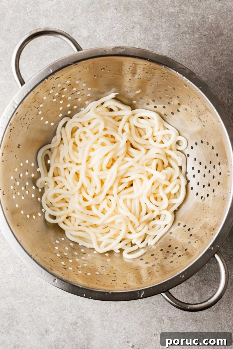 Kake Udon: Classic Japanese Broth Noodle Soup Recipe 6 A colander with rinsed and drained udon noodles looking plump and chewy.