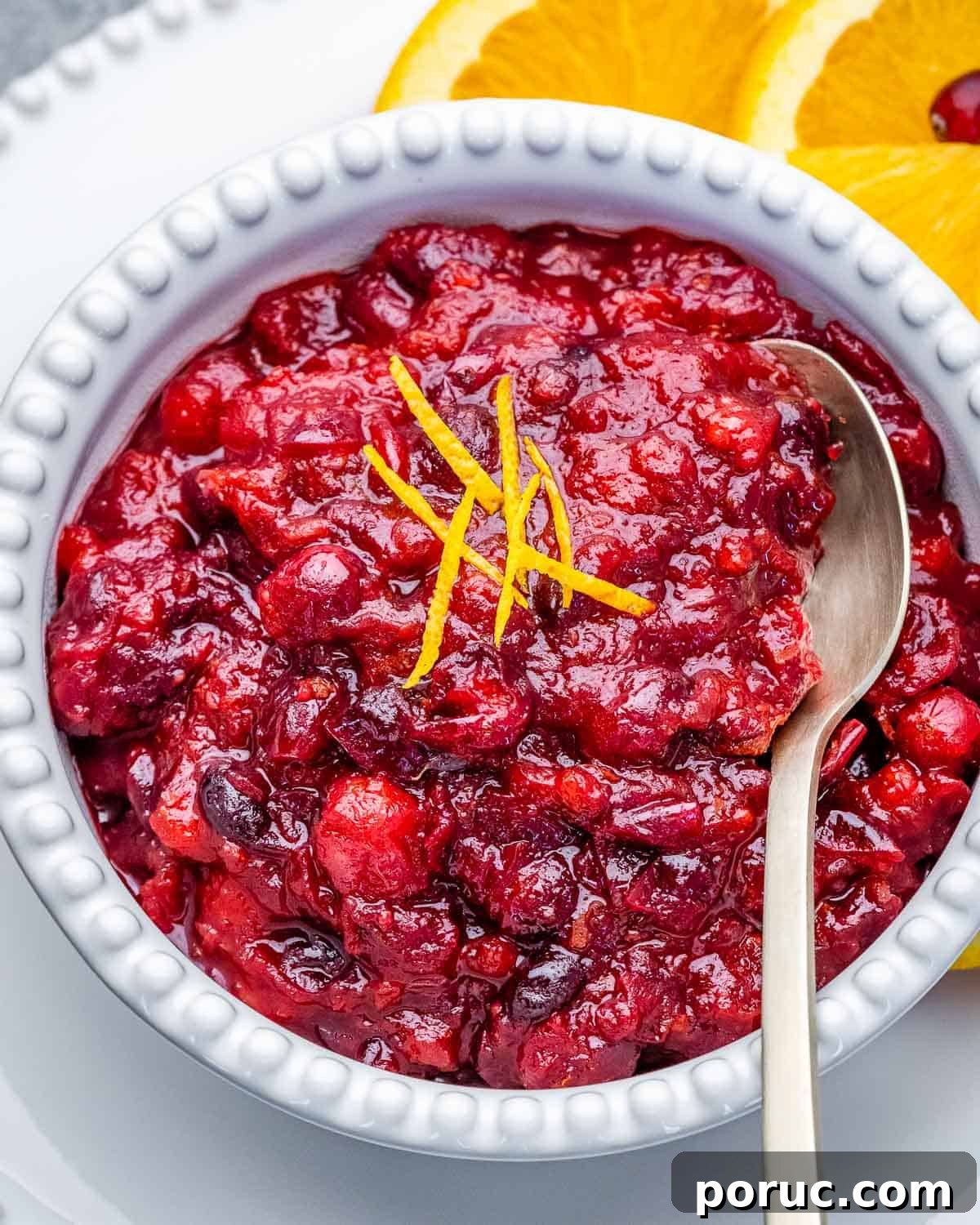 Tangy Cranberry Orange Sauce Recipe for Holidays and Leftovers 2 A white bowl filled with cranberry sauce with a cinnamon stick in bowl.