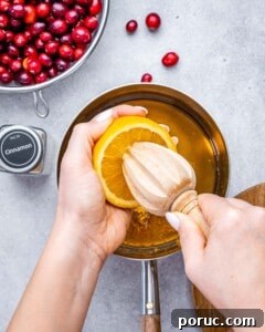 Tangy Cranberry Orange Sauce Recipe for Holidays and Leftovers 11 Squeezing fresh orange juice into a saucepan with maple syrup and orange zest.