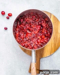 Tangy Cranberry Orange Sauce Recipe for Holidays and Leftovers 13 Cranberry orange sauce cooking in a saucepan.
