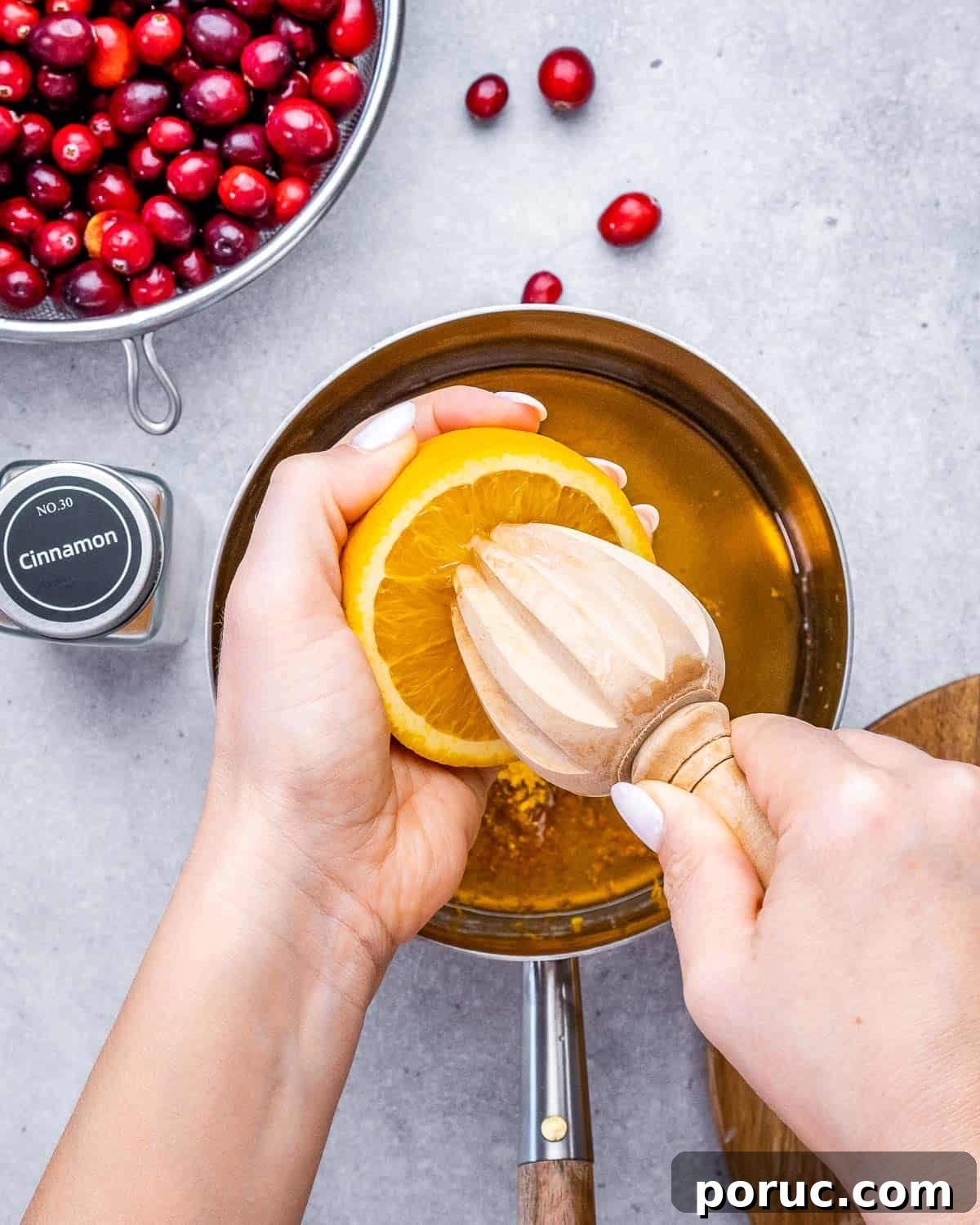 Tangy Cranberry Orange Sauce Recipe for Holidays and Leftovers 3 Squeezing fresh orange juice into a saucepan with maple syrup and orange zest.