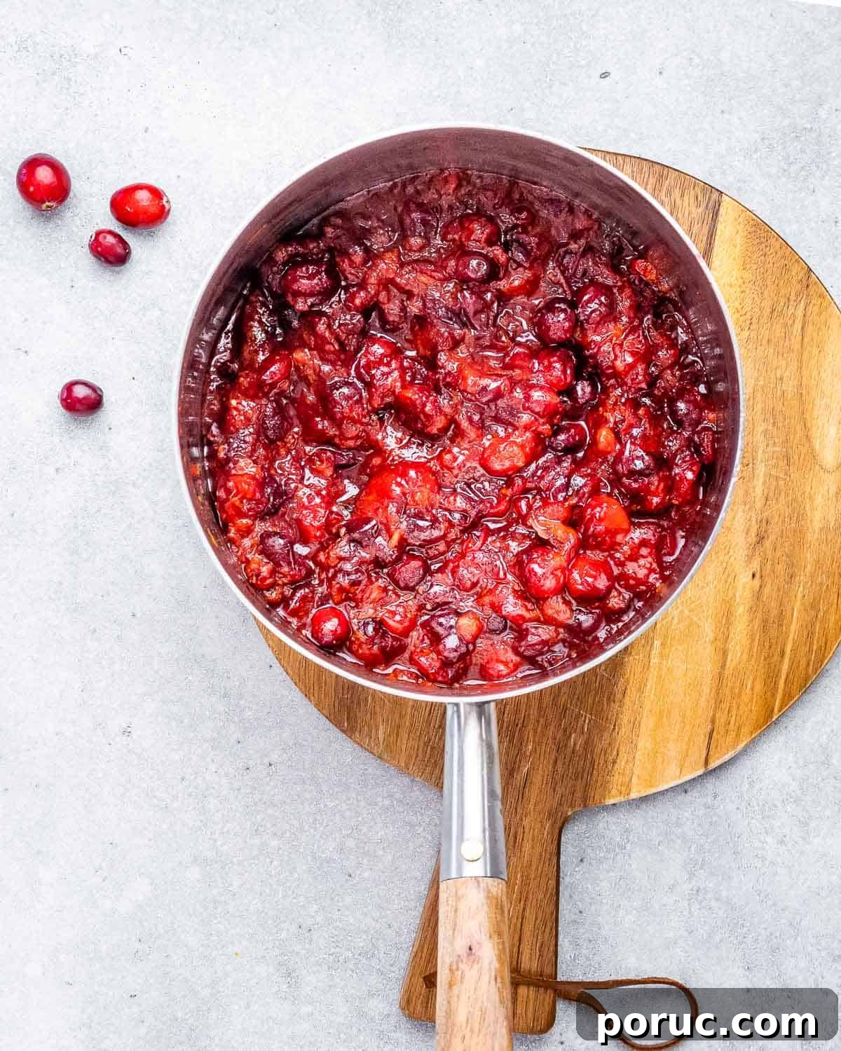 Tangy Cranberry Orange Sauce Recipe for Holidays and Leftovers 5 Cranberry orange sauce cooking in a saucepan.