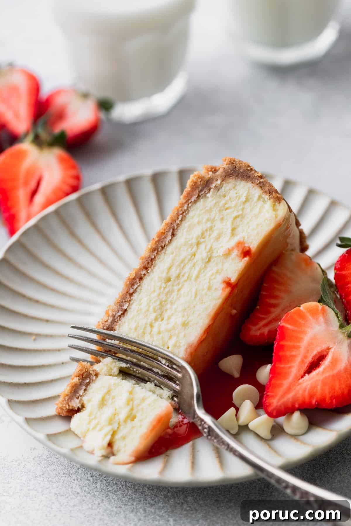 One slice of cheesecake on a plate with a fork inserted.