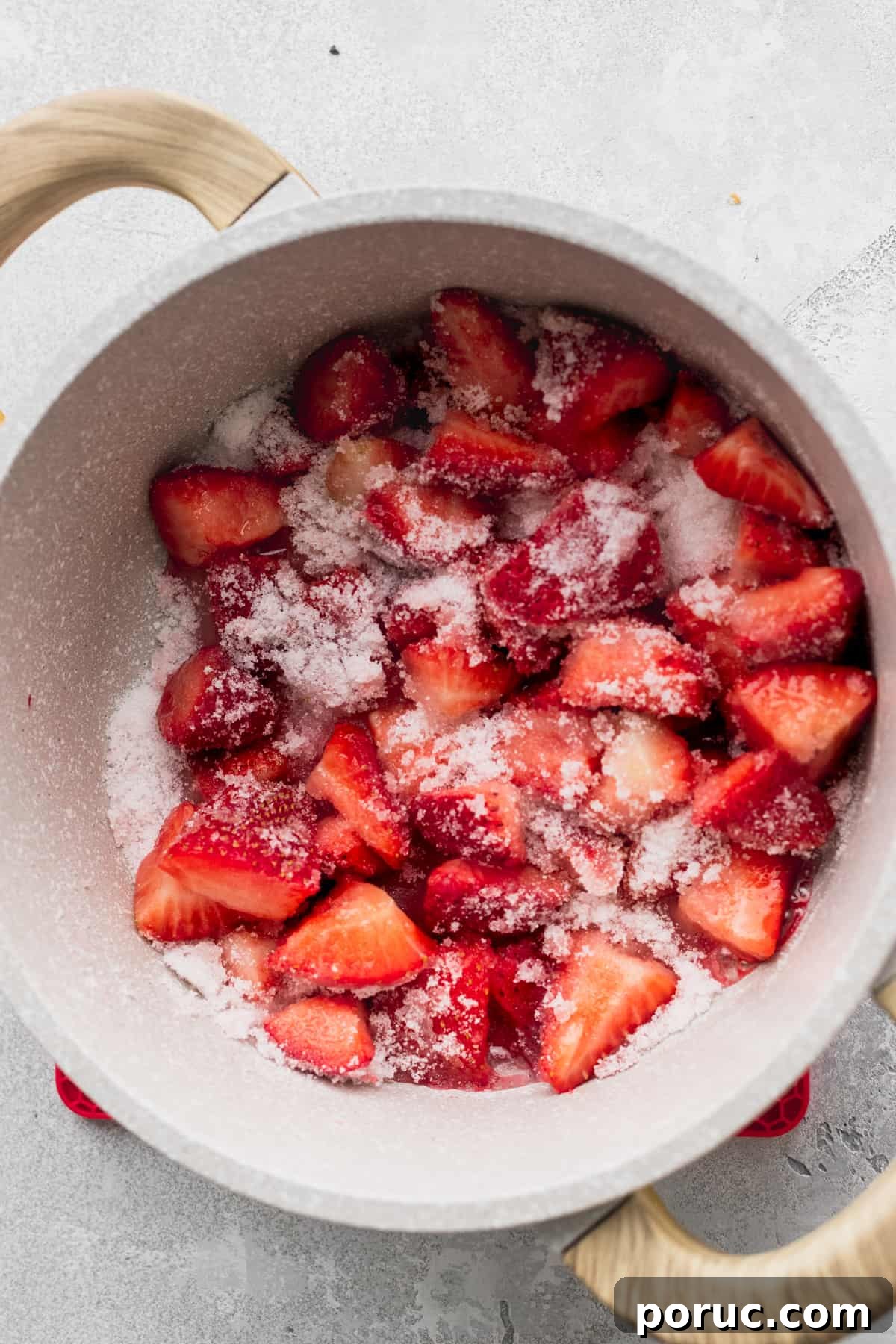 Strawberries covered in sugar in a pot.
