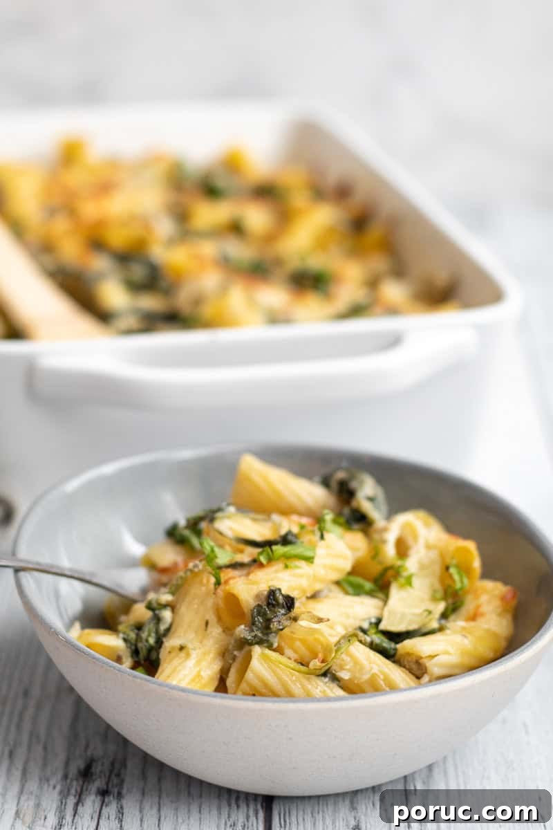 Spinach and Artichoke Pasta Bake with 7 Simple Ingredients 6 spinach artichoke pasta in a bowl with the baking dish behind.