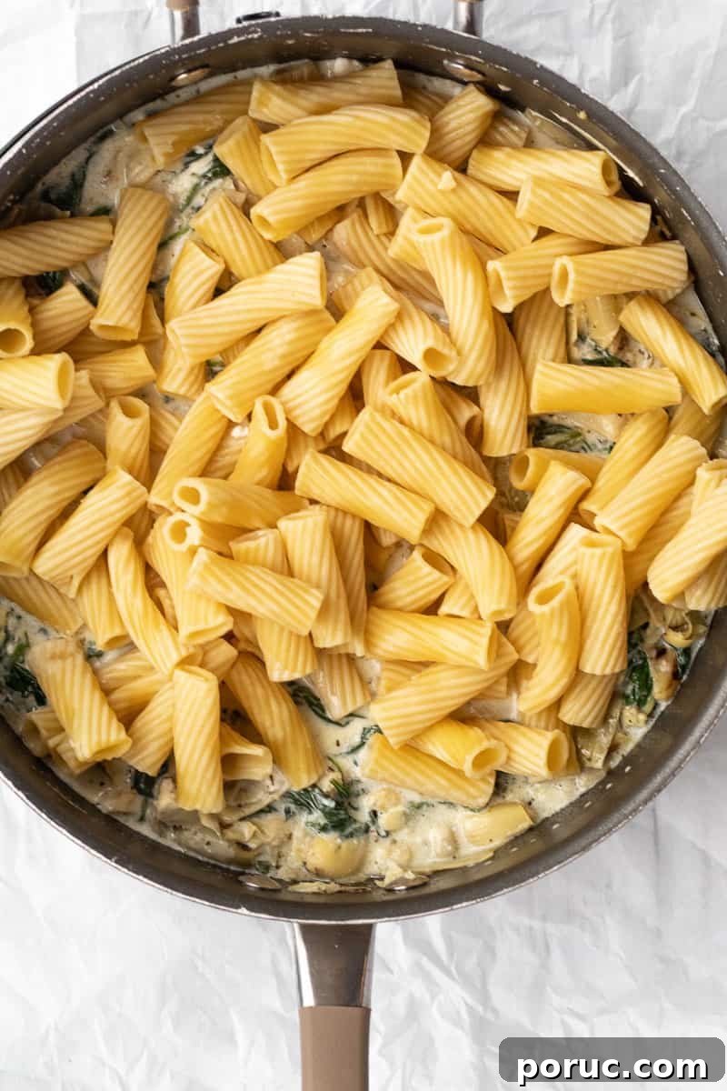 Spinach and Artichoke Pasta Bake with 7 Simple Ingredients 10 pasta added to a saute pan