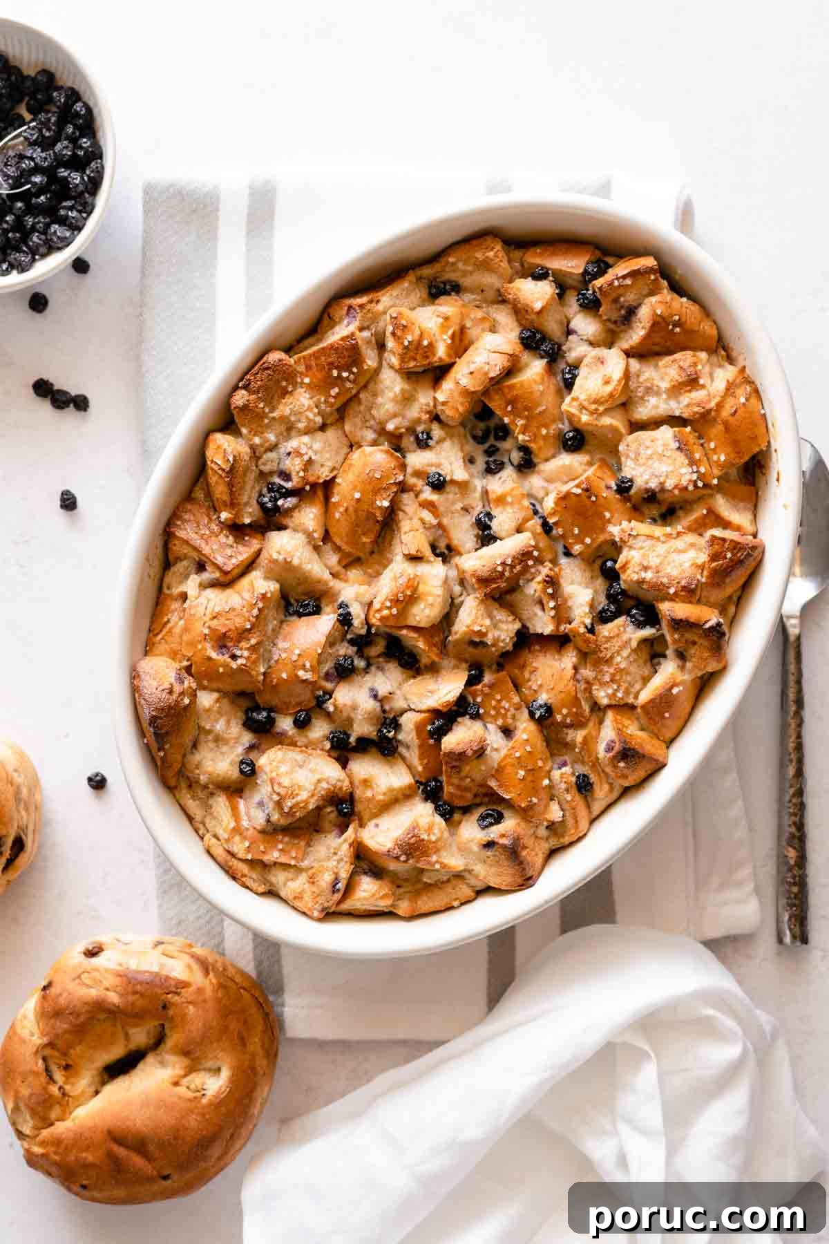 bread pudding with dried blueberries in oval casserole dish.