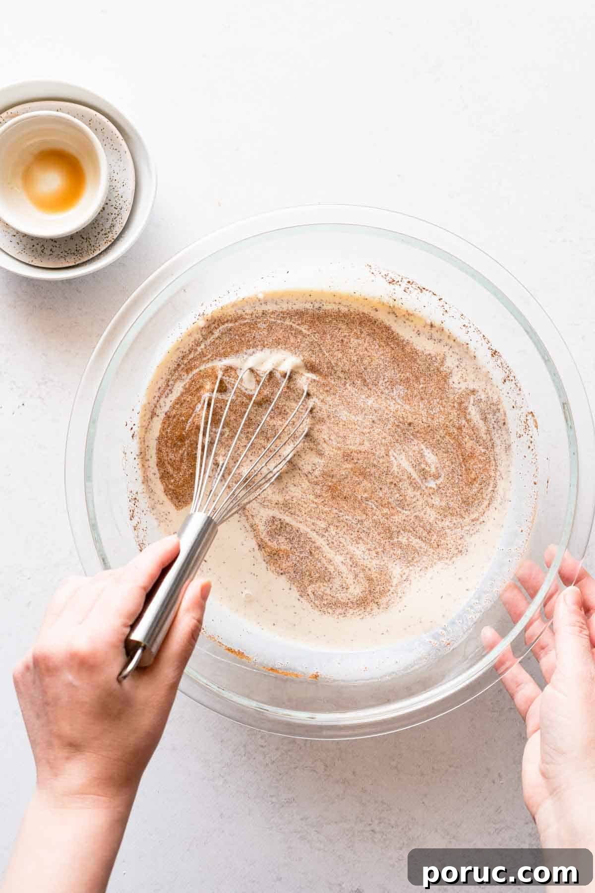 liquid ingredients for bagel bread pudding being whisked in glass bowl.