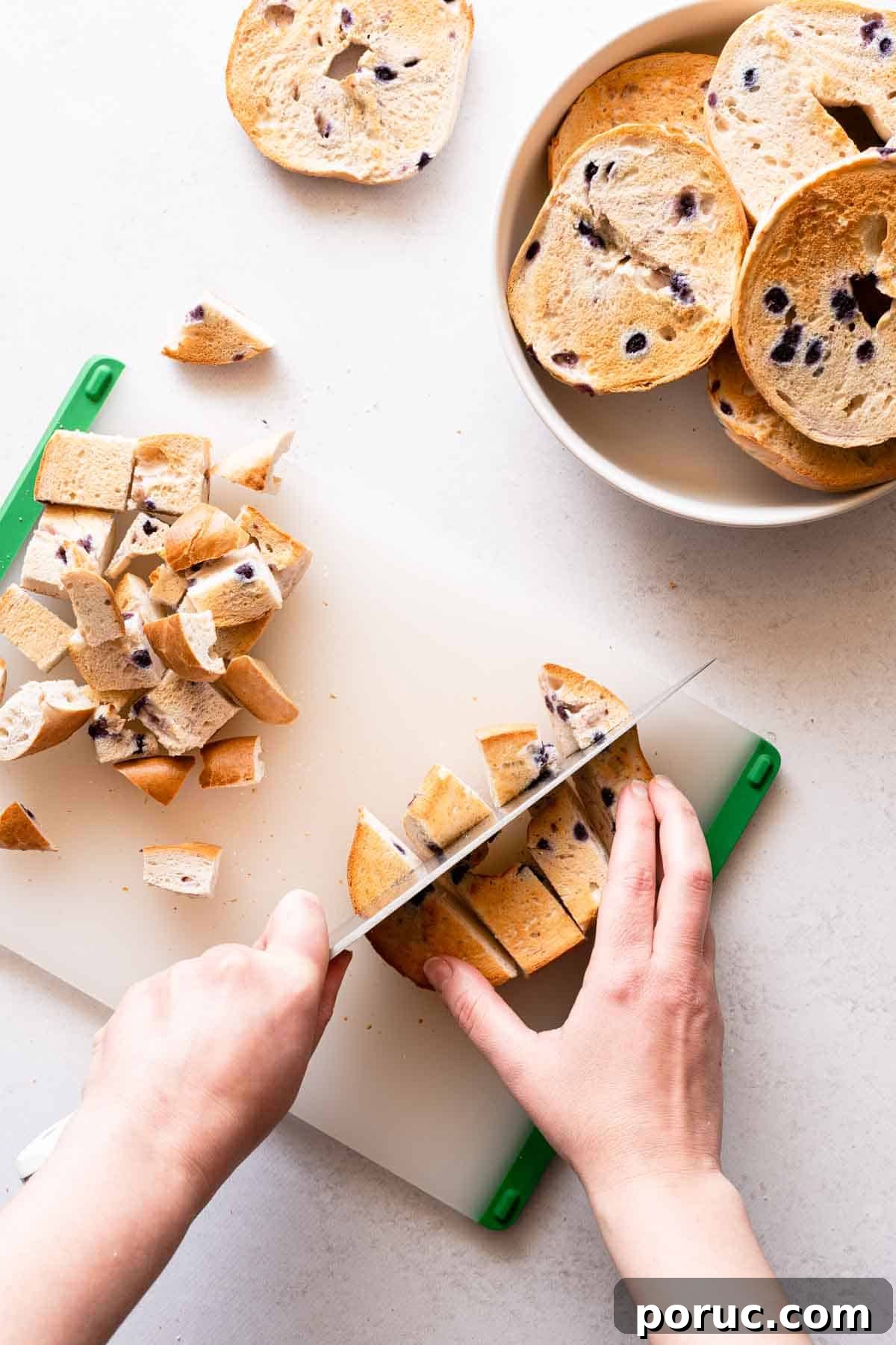 bagels being cut into small pieces on a cutting board.