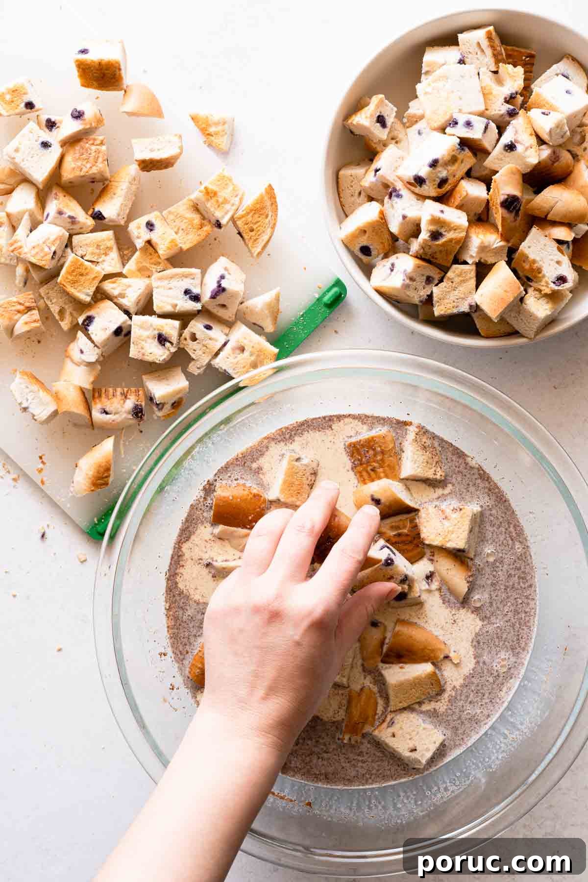 bagel pieces being added into the liquid ingredients for the bread pudding.