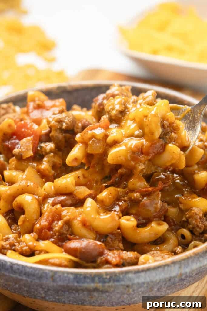 A bowl of chili mac with ground beef, elbow macaroni, tomatoes, and melted cheese.