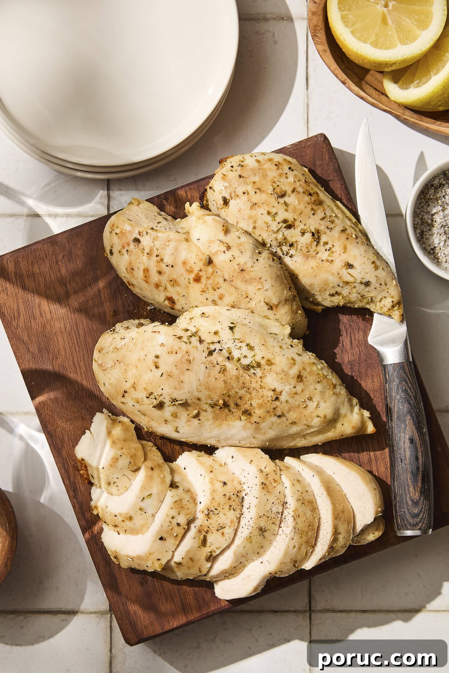 Four baked chicken breasts with one sliced with lemon herb marinade.