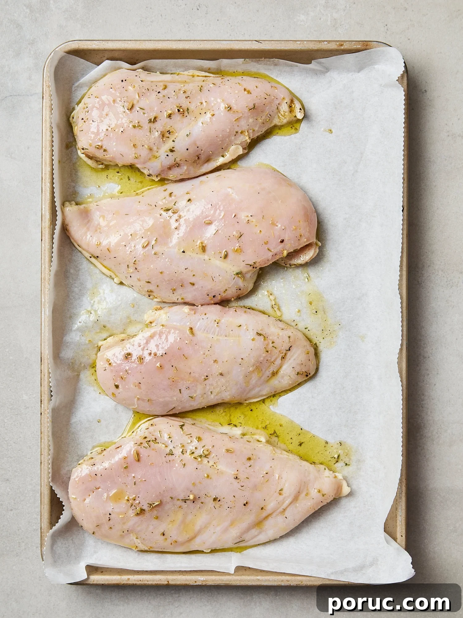 Uncooked chicken breast pieces on parchment-lined baking sheet before baking.