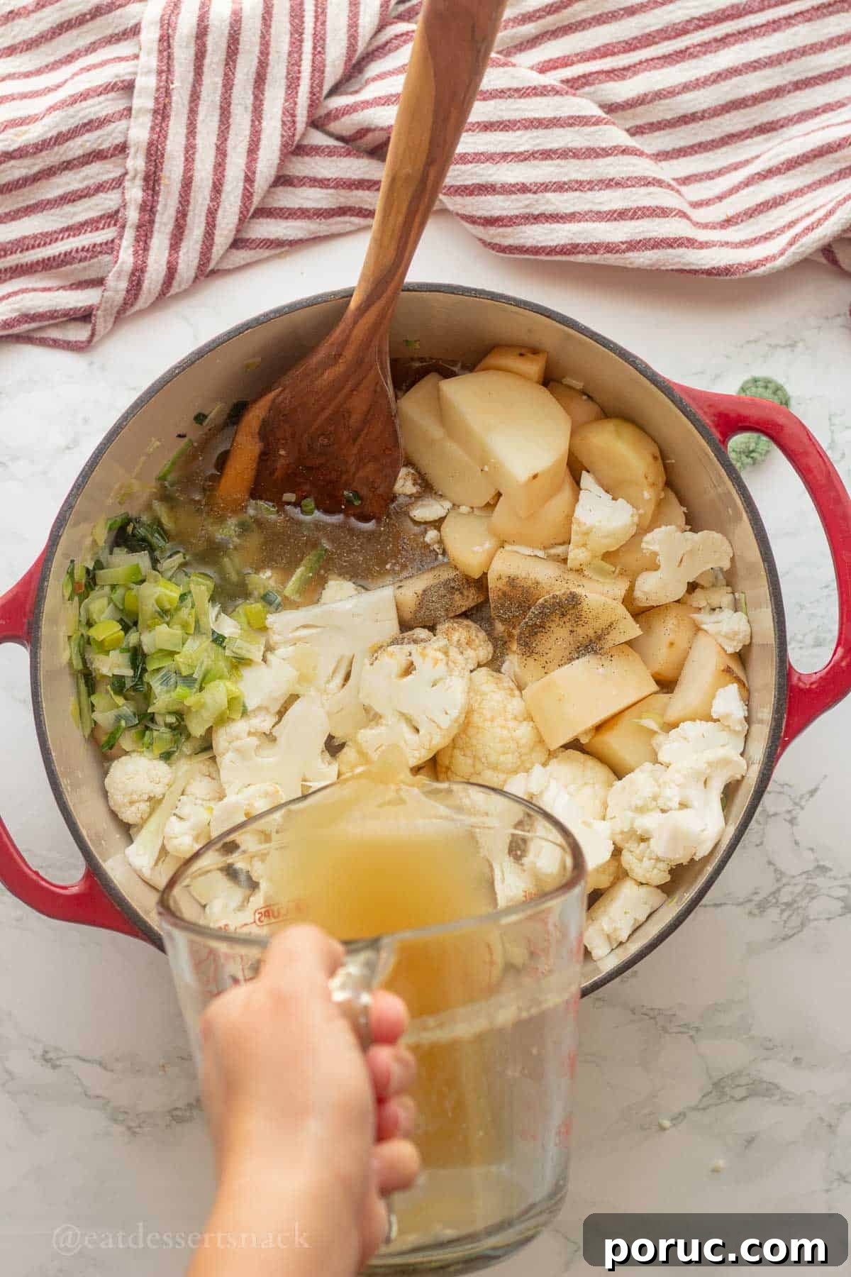Creamy Potato, Leek & Cauliflower Soup Recipe 6 Pouring chicken broth into pot of raw cauliflower and potatoes.