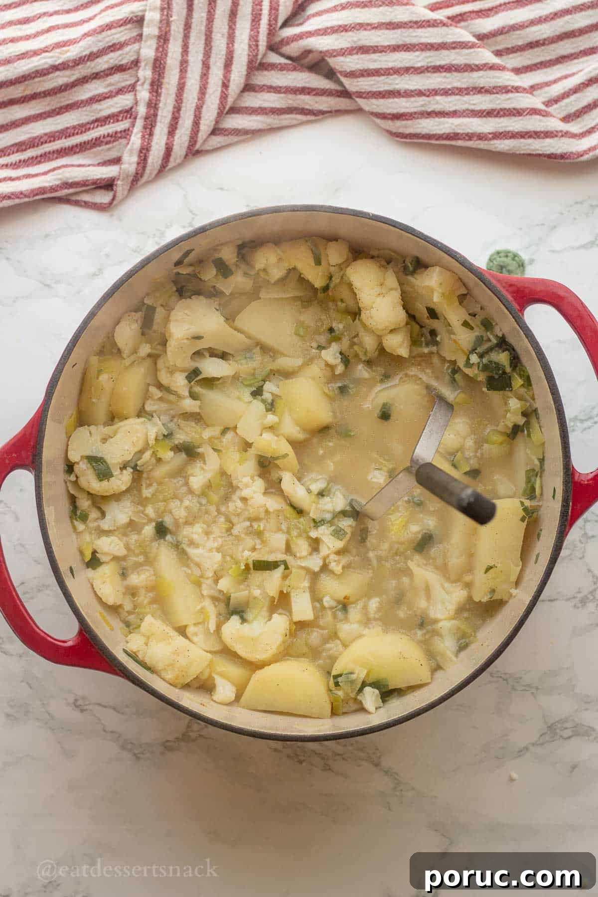 Creamy Potato, Leek & Cauliflower Soup Recipe 7 Mashing potatoes and cauliflower in soup with potato masher.