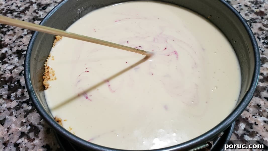 Lemon Blueberry Cheesecake Recipe: Creamy No-Bake Dessert 9 a skewer swirling blueberry sauce through lemon cheesecake filling.