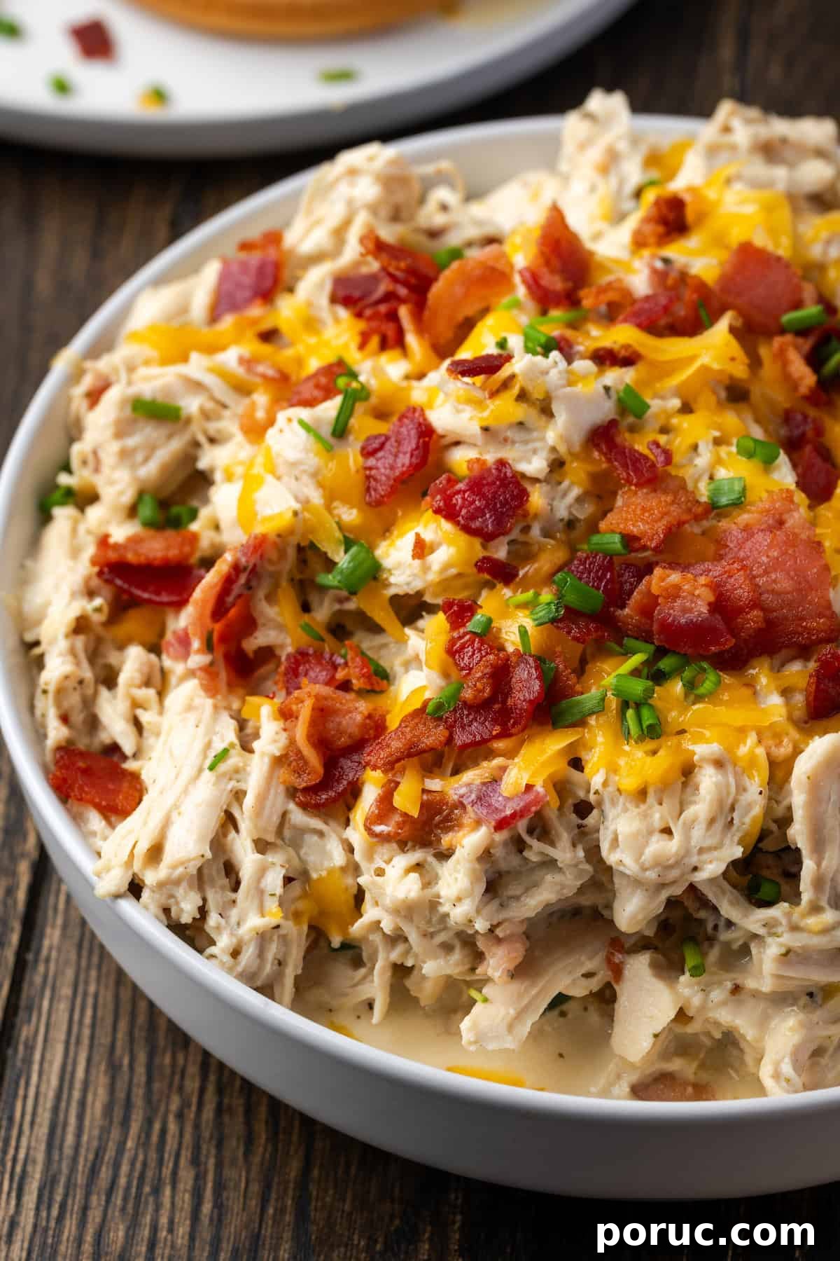 A bowl of Instant Pot crack chicken topped with crumbled bacon, cheese, and chives.